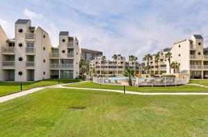 um grande quintal relvado em frente a dois edifícios de apartamentos em Spectacular Ocean-View Condo in Beachfront Resort em South Padre Island