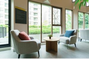 a lobby with two chairs and a table and windows at Sathon-Charoen Nakhon Condo in Bangkok