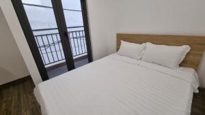 a bedroom with a white bed and a large window at Era Apartment Khuc Thua Du in Hanoi