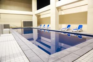 a swimming pool with blue chairs in a building at Sotogrande Hotel Katipunan in Manila