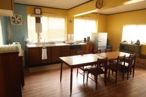 a kitchen with a wooden table and a table and chairs at 奈多みどり荘 Nada Beach House in Kitsuki