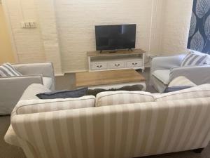 a living room with two couches and a flat screen tv at Gallipoli House- The Loft Apartment in Narrabri