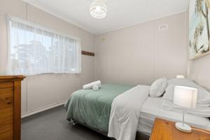 une chambre blanche avec un lit et une table dans l'établissement Wanderer by Experience Jervis Bay, à Sanctuary Point
