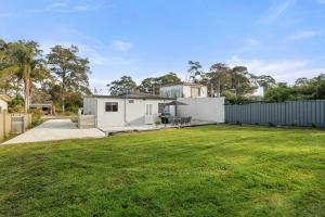 a house with a large yard with a fence at Wanderer by Experience Jervis Bay in Sanctuary Point