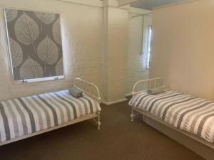 a room with two beds and a window at Gallipoli House- The Loft Apartment in Narrabri