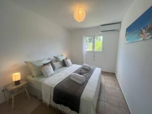 1 dormitorio blanco con 1 cama grande con lámpara en Dans la douceur de Montebello, en Petit-Bourg