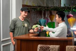 a man handing a man something at a counter at La Renta Center Hotel & Spa in Hanoi