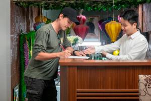 two men standing at a bar writing on a paper at La Renta Center Hotel & Spa in Hanoi
