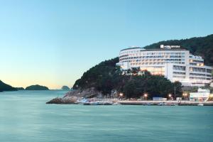 a large building on a hill next to a body of water at Hotel Riviera Geoje in Geoje 