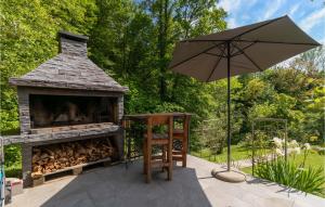 un patio con chimenea al aire libre y sombrilla en Stunning Home In Brod Na Kupi With Wifi, en Brod na Kupi