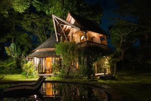 une maison la nuit avec un étang devant elle dans l'établissement Green Tree House Villa Ubud, à Ubud