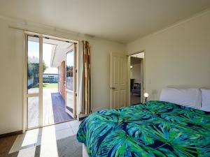 a bedroom with a bed and a sliding glass door at Torquay Central - Kaikoura Holiday Home in Kaikoura