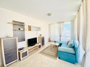 ein Wohnzimmer mit einer blauen Couch und einem Fernseher in der Unterkunft Apartments in Sunny Island Complex in Tschernomorez