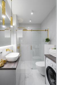 ein weißes Badezimmer mit einem Waschbecken und einer Waschmaschine in der Unterkunft Exclusive Crystal Apartment in Krakau