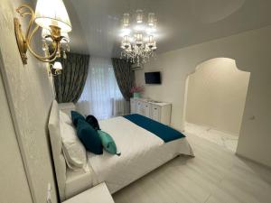 Un dormitorio con una cama con almohadas azules y una lámpara de araña. en White Apartment, en Dnipro