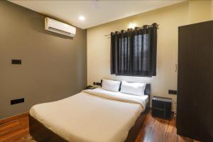 a small room with a bed and a window at FabHotel Lemon Grass - Assi Ghat in Varanasi