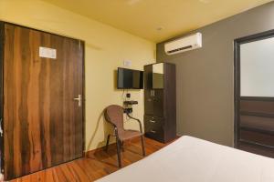 a room with a bed and a chair and a door at FabHotel Lemon Grass - Assi Ghat in Varanasi