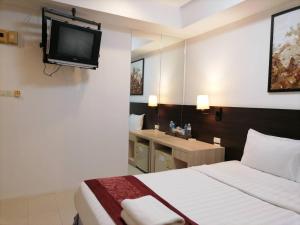 una camera d'albergo con letto e TV a parete di Amici Miei Guest House a Patong Beach