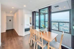 una sala da pranzo con tavolo, sedie e una grande finestra di Magnificent Harbour View Skytower View Apartment in CBD ad Auckland