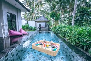 Capung Asri Eco Luxury Resort with Private Pool Villas في Bedahulu: قارب صغير وسط مسبح