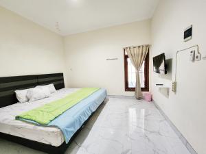 ein weißes Schlafzimmer mit einem Bett und einem Fenster in der Unterkunft Surabaya Homey near UNAIR Syariah in Surabaya