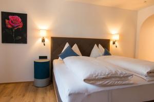 ein Schlafzimmer mit einem großen weißen Bett mit blauen Kissen in der Unterkunft Pension Appartements Alpenblick in Maria Alm am Steinernen Meer