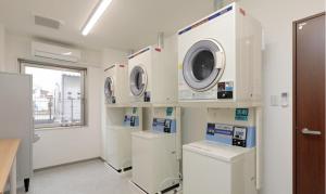 a laundry room with three washing machines and a window at A&Bee HOTEL in Oita
