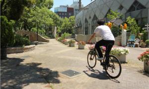Un uomo in bicicletta in un parco di A&Bee HOTEL a Oita