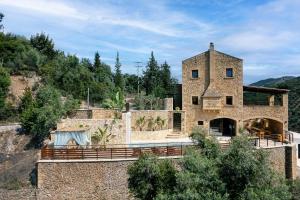una casa de piedra en una colina con árboles en Kotinos Luxury Villa, en La Canea