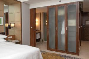 a bedroom with a bed and a large glass closet at Sheraton Grand Shanghai Pudong Hotel & Residences in Shanghai