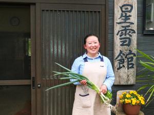 Un homme dans un tablier tenant un bouquet de fleurs dans l'établissement noukanoyado seisetsukan, à Senboku