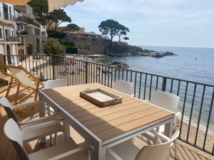 una mesa de madera y sillas en un balcón con vistas al océano en Playa Canadell MAR G primera linea de mar con terraza, en Calella de Palafrugell