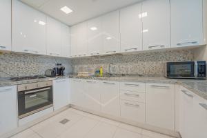a white kitchen with white cabinets and a microwave at KeyHost - Regent Court JVC - K180 in Dubai