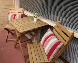 a wooden picnic table and two chairs on a porch at Elwood Beach Apartment (2 min walk from beach) in Melbourne