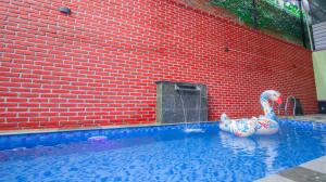 a swimming pool with a swan in a brick wall at Villa Violet 2 Private Pool by Masterpiece Villa in Batu