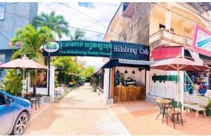 una calle con mesas, sillas y sombrillas frente a un edificio en The Billabong Guesthouse, en Kampot