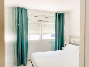 een slaapkamer met een bed en een raam met groene gordijnen bij Dalex in Salou
