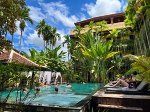 einen Pool in einem Resort mit Leuten darin in der Unterkunft Residence Indochine Suite in Siem Reap