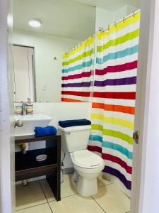 a bathroom with a toilet and a rainbow shower curtain at Nicoland Playa y piscina La Serena in La Serena