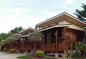 a log cabin with wooden benches in front of it at พบรักรีสอร์ท Pobruk resort in Tha Bo