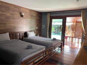 a bedroom with two beds and a door to a patio at พบรักรีสอร์ท Pobruk resort in Tha Bo