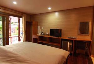 a bedroom with a bed and a desk with a television at พบรักรีสอร์ท Pobruk resort in Tha Bo