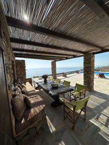 un patio con mesa, sillas y el océano en Divine Blue Villa Nano in Koundouros Kea Cyclades with pool and sea view, en Koundouros