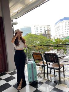 a woman standing with a suitcase on a balcony at Cheriladyhomestayhue in Hue