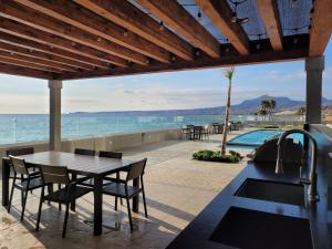 a patio with a table and chairs and a swimming pool at Beachfront Luxury Seaside Condo + Pool & Jacuzzi in Rosarito