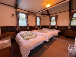 a bedroom with three beds in a room with windows at Hotel Sejour Mint in Hakuba in Hakuba