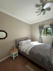 een slaapkamer met een bed en een plafondventilator bij The stables in Gillitts