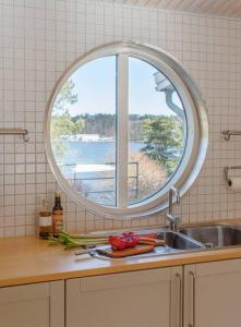 - un évier de cuisine avec une fenêtre ronde au-dessus dans l'établissement Spectacular lake plot, Stockholm archipelago, à Dalarö