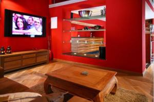 a living room with red walls and a flat screen tv at Jacuzzi - BBq - Jardin - Garden Lodge - Le Tulipier in Olne +33 photos