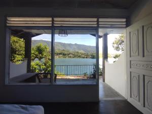 a room with a view of a lake through a window at Hub Tata Guesthouse in Tuk Tuk